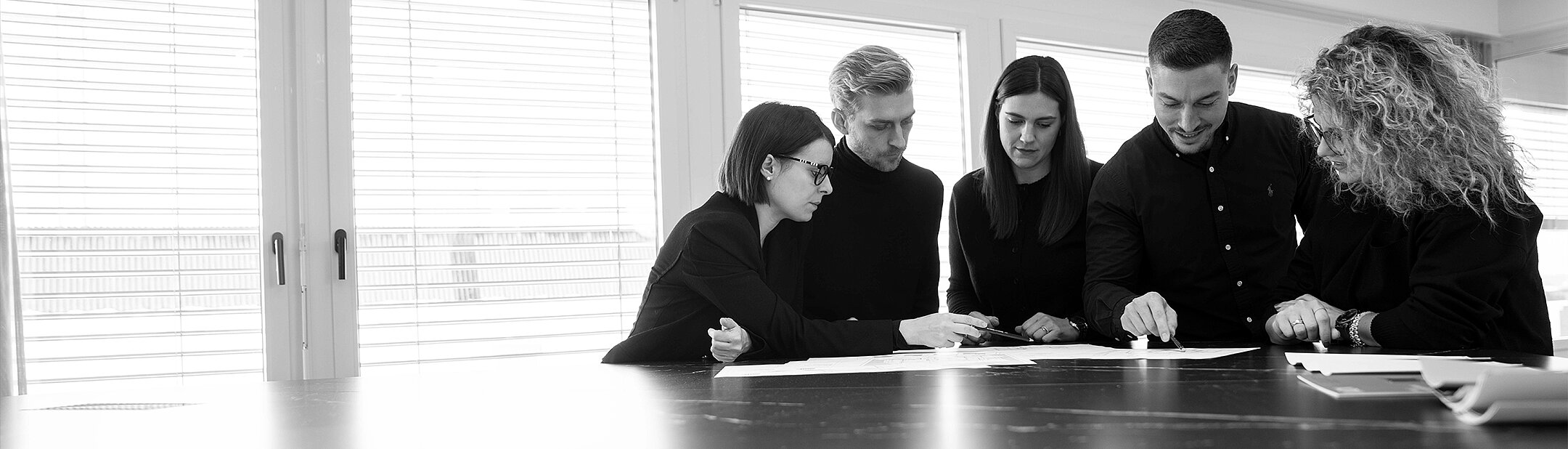 Photograph of three interior designers in black and white discussing a design.