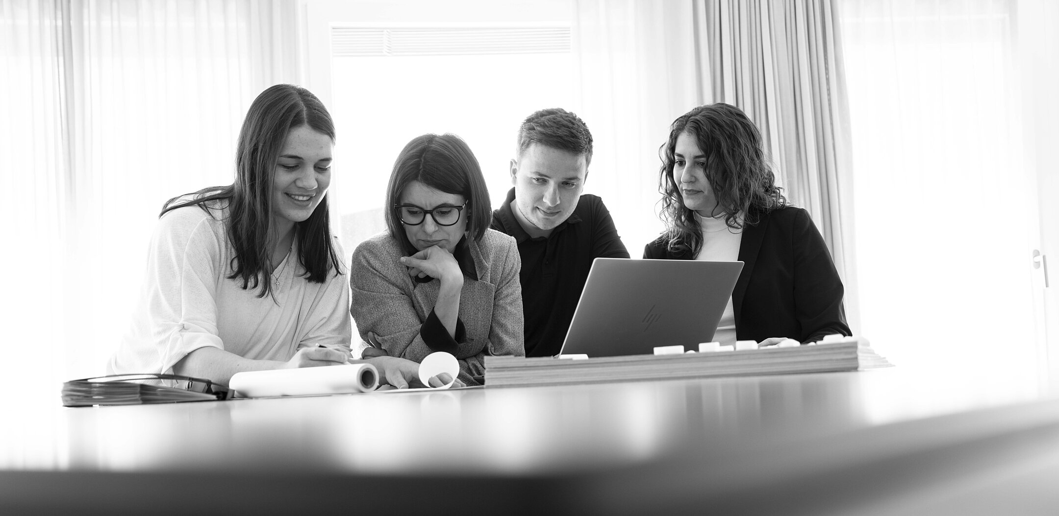 Header, Kontakt Schwarz-weiss Fotografie von der Zusammenarbeit der Mitarbeitenden.