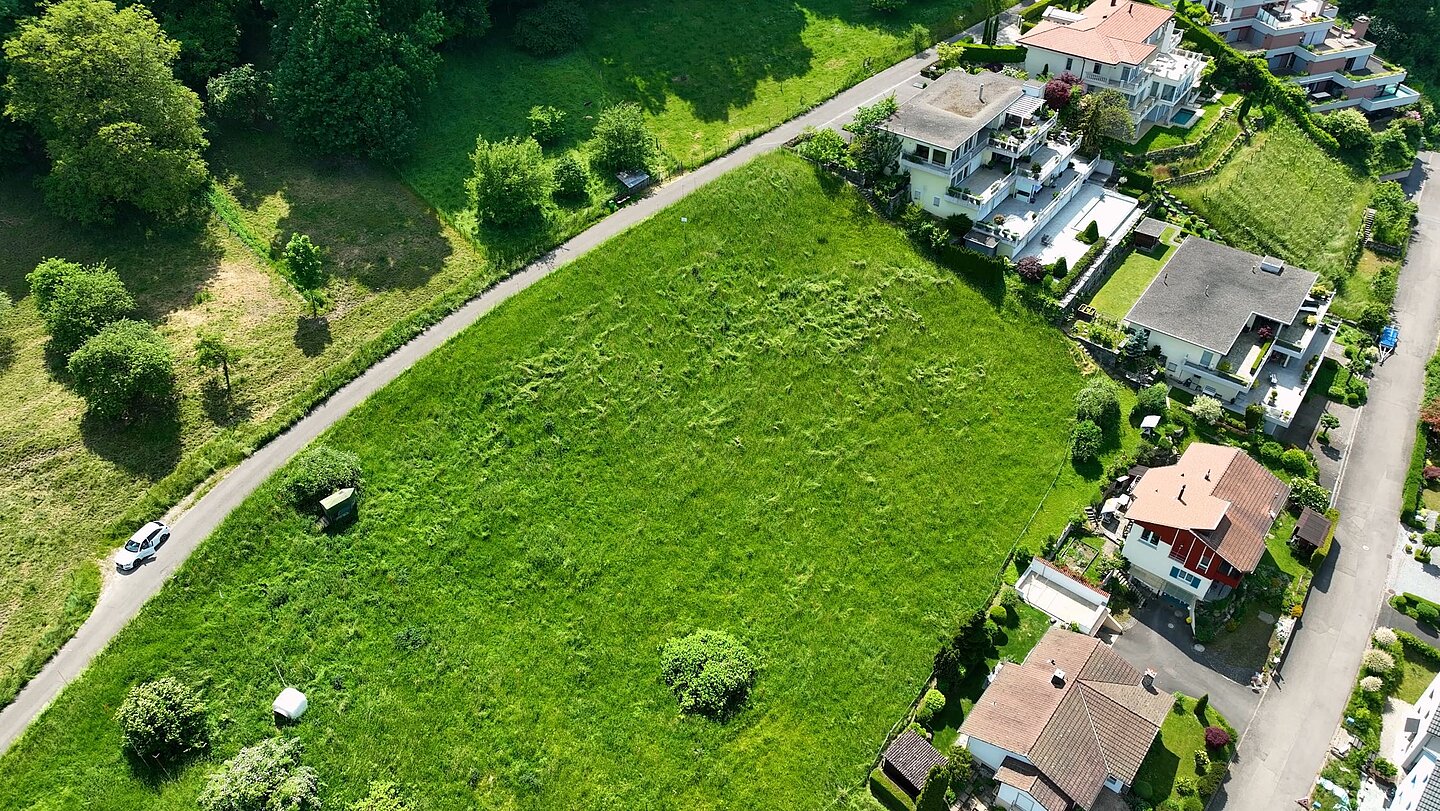 Drohnenaufnahme eines Baugrundstücks mit Hanglage in der Schweiz.